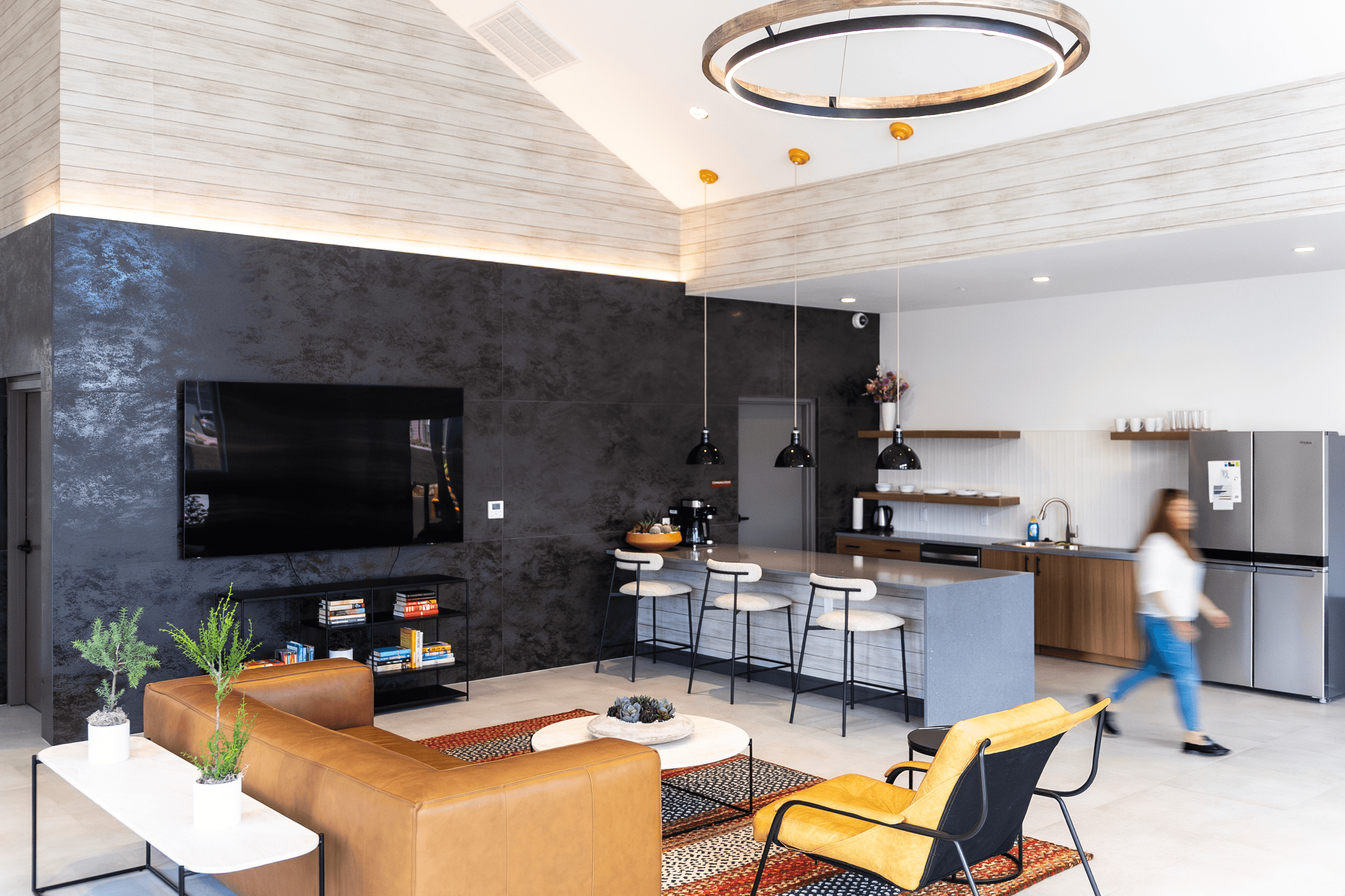 A woman walks through a modern kitchen and living room.